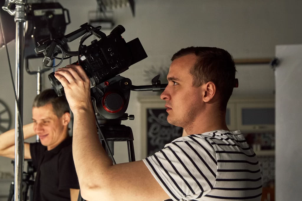 A videographer adjusting equipment on set.